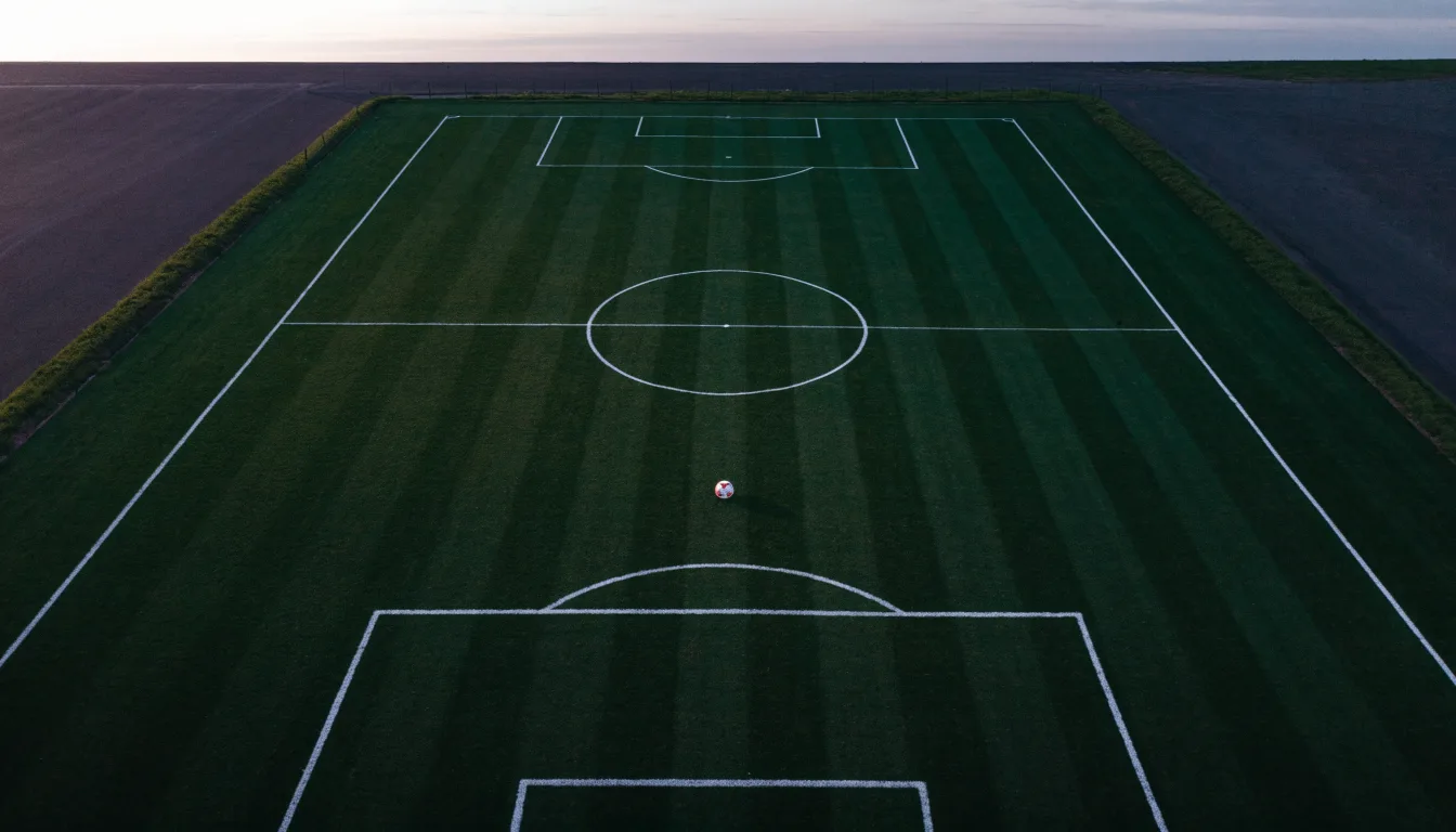 Ein Fussballplatz von oben gesehen, die Linien bilden ein helles Muster auf dem Rasen, Drohnenperspektive in der Morgendämmerung.